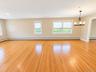 Combined Living room and dining room with hardwood flooring, multiple windows with roller shades, recessed lighting, and a dark-toned chandelier