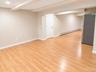 Spacious open-concept room with wood-finish flooring, white trim, and a white paneled door