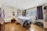 Hardwood flooring, painted walls, and a large window with privacy curtains