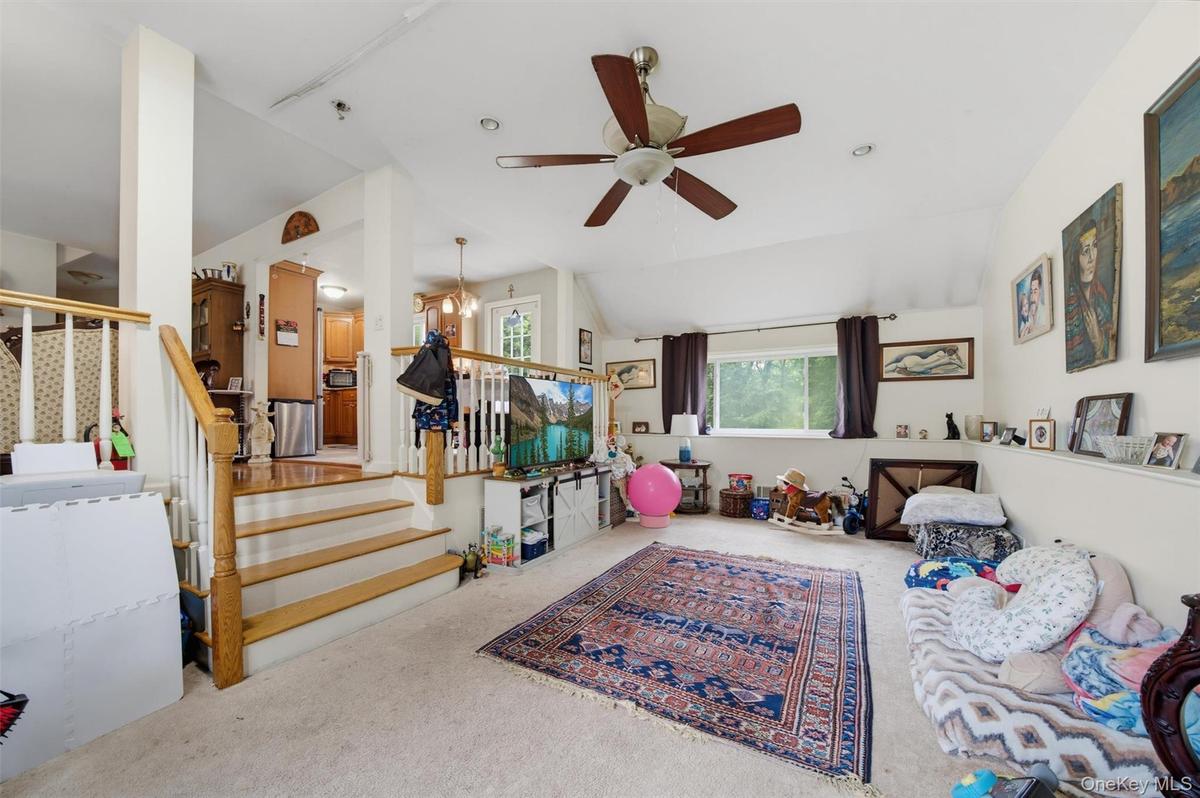 Carpeted living area with a vaulted ceiling, recessed lighting, and a ceiling fan