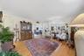 Wood-finish flooring throughout, with a wide opening leading to a dining area with a chandelier