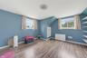 Sloped ceiling room featuring wood-finish flooring, recessed shelving, built-in wall shelving, dual windows, and a flush-mount ceiling light fixture