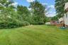Expansive green lawn with mature "Privacy trees" and a wood-slatted deck