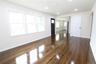 Spacious open living area showcasing refinished hardwood flooring, abundant natural light from triple-pane windows, recessed ceiling lighting, and cle