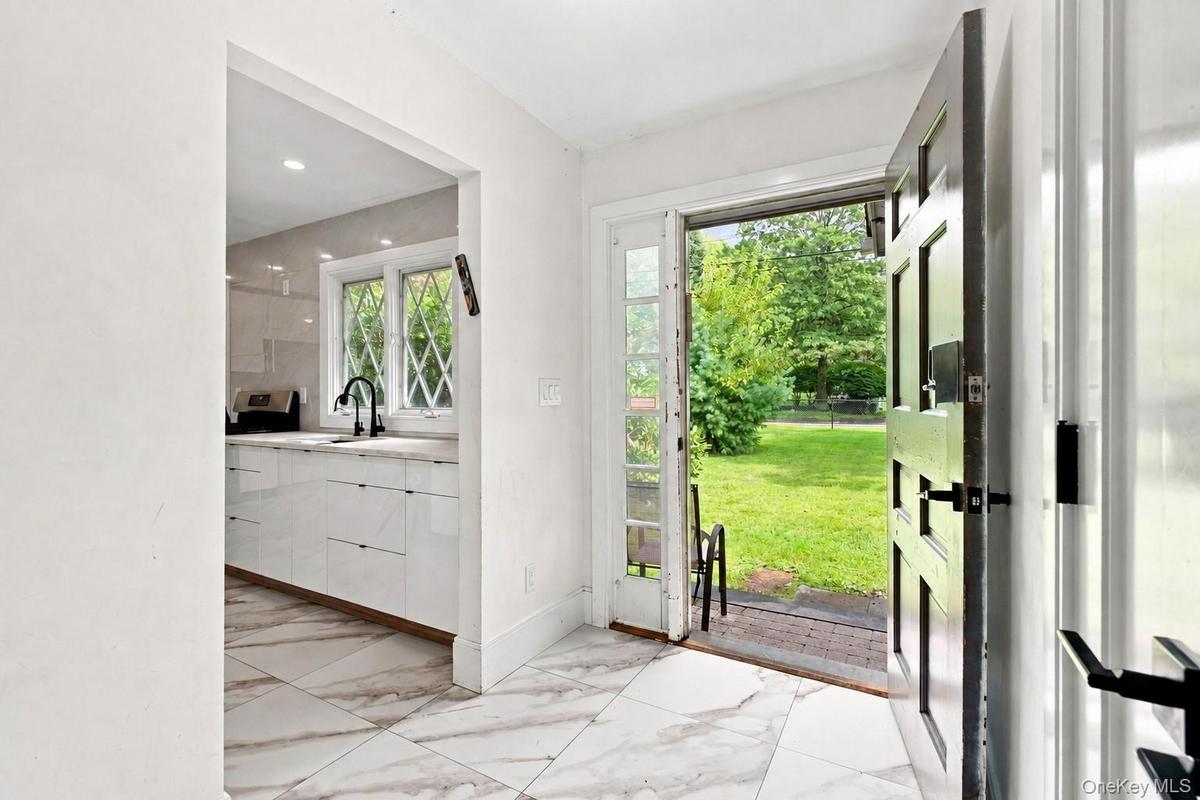 Marble-look tile flooring, entryway with dark-paneled door,