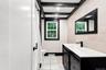 Bathroom featuring exposed ceiling beams, horizontal-set wall tile, a window with dark trim, a dark vanity with an integrated sink, and matte black fi