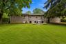 Expansive green lawn with mature trees and a rear patio