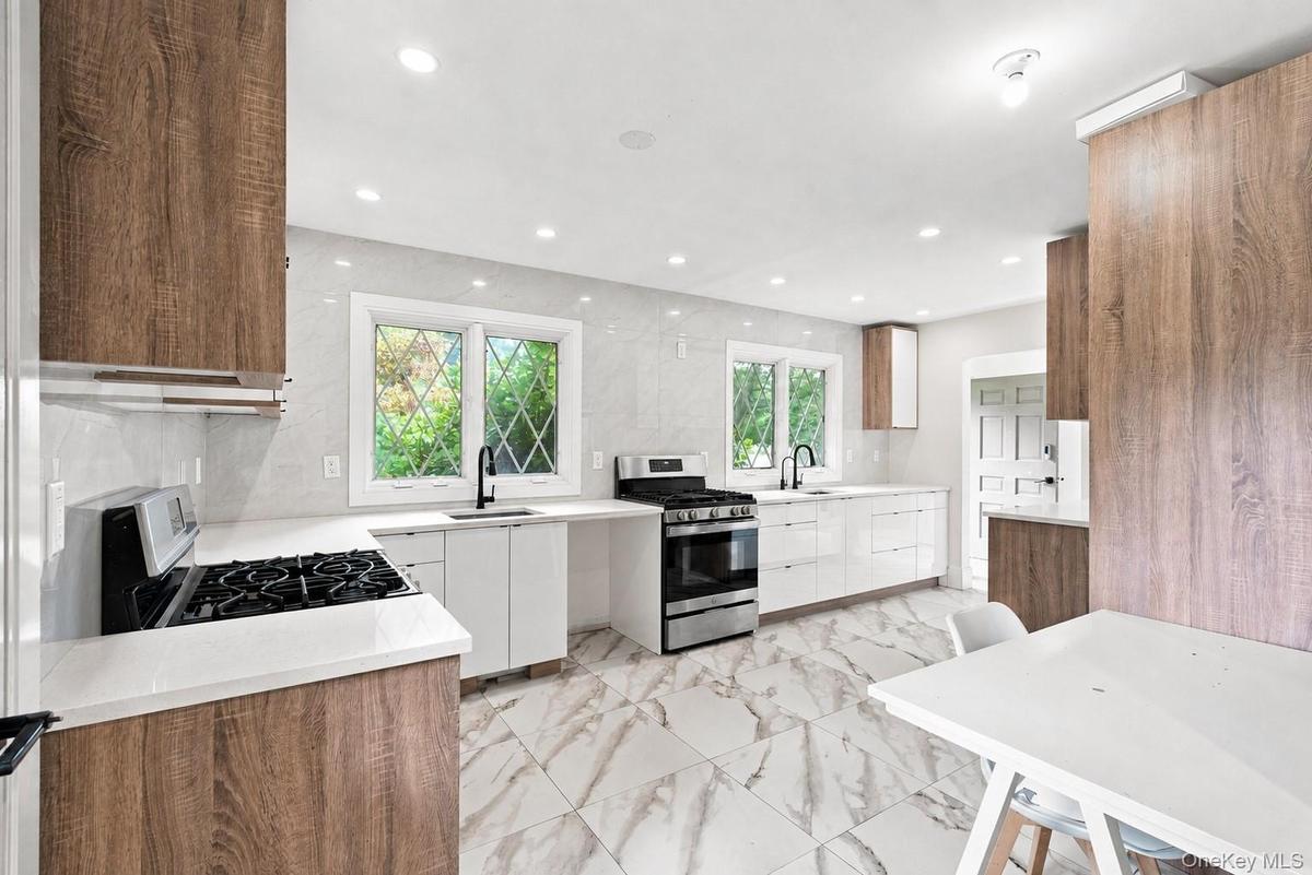 Contemporary kitchen featuring wood-finish cabinetry, white slab cabinet fronts, white countertops, and a full tile backsplash