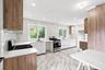 Contemporary kitchen featuring wood-finish cabinetry, white slab cabinet fronts, white countertops, and a full tile backsplash