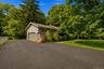 Siding exterior with an attached garage, paved driveway, and manicured lawn surrounded by mature trees