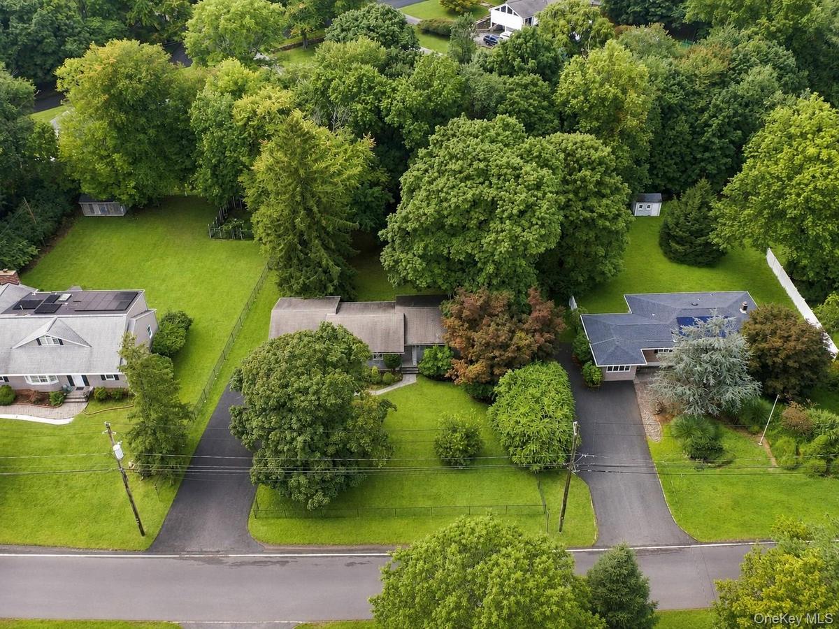 Expansive property featuring lush green lawns, mature trees, and paved driveways