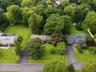 Expansive property featuring lush green lawns, mature trees, and paved driveways