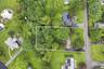 Expansive lot featuring mature trees and a paved driveway, with direct road access