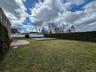Expansive green lawn with a brick paver patio, mature privacy hedges, and a covered swimming pool