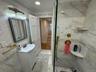 Shower with full-height tile surround, brass fixtures, and built-in shelving