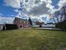 Brick exterior with multiple windows, multiple sliding glass doors, a patio, a lush lawn, and an in-ground pool