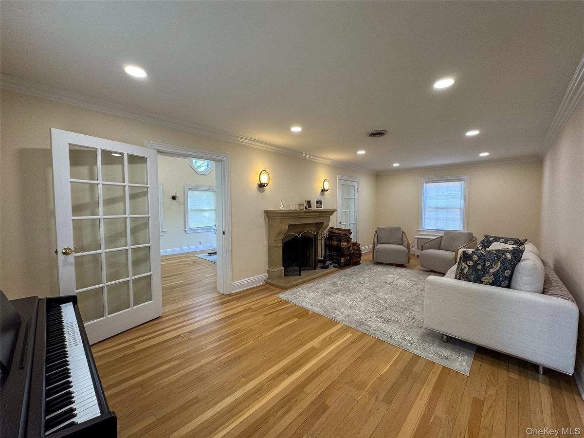 Hardwood flooring, recessed lighting, ornate fireplace with stone surround, crown molding, and French doors