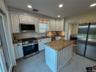 Kitchen featuring white cabinetry, granite countertops, stainless steel appliances, a center island, and tile flooring