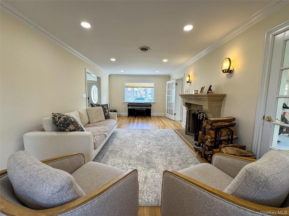 Hardwood flooring, crown molding, recessed lighting, stone fireplace, and double French doors