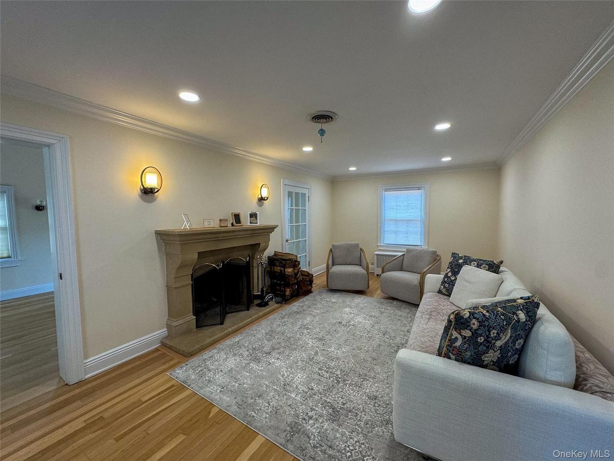 Recessed lighting, crown molding, wood-finish flooring, stone fireplace, and wall sconces
