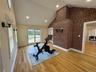 Vaulted ceiling with recessed lighting, exposed brick wall, light wood-finish flooring, sliding glass doors, and wall sconces
