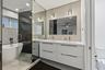 Modern bathroom featuring a floating dual vanity with integrated sinks, a freestanding tub, and a glass-enclosed shower
