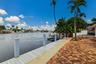 Waterfront property featuring a private dock, brick paver patio, lush tropical landscaping, and a pool with an attached spa