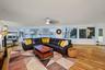 Expansive windows providing a water view, light wood-finish flooring, and a ceiling fan with integrated lighting