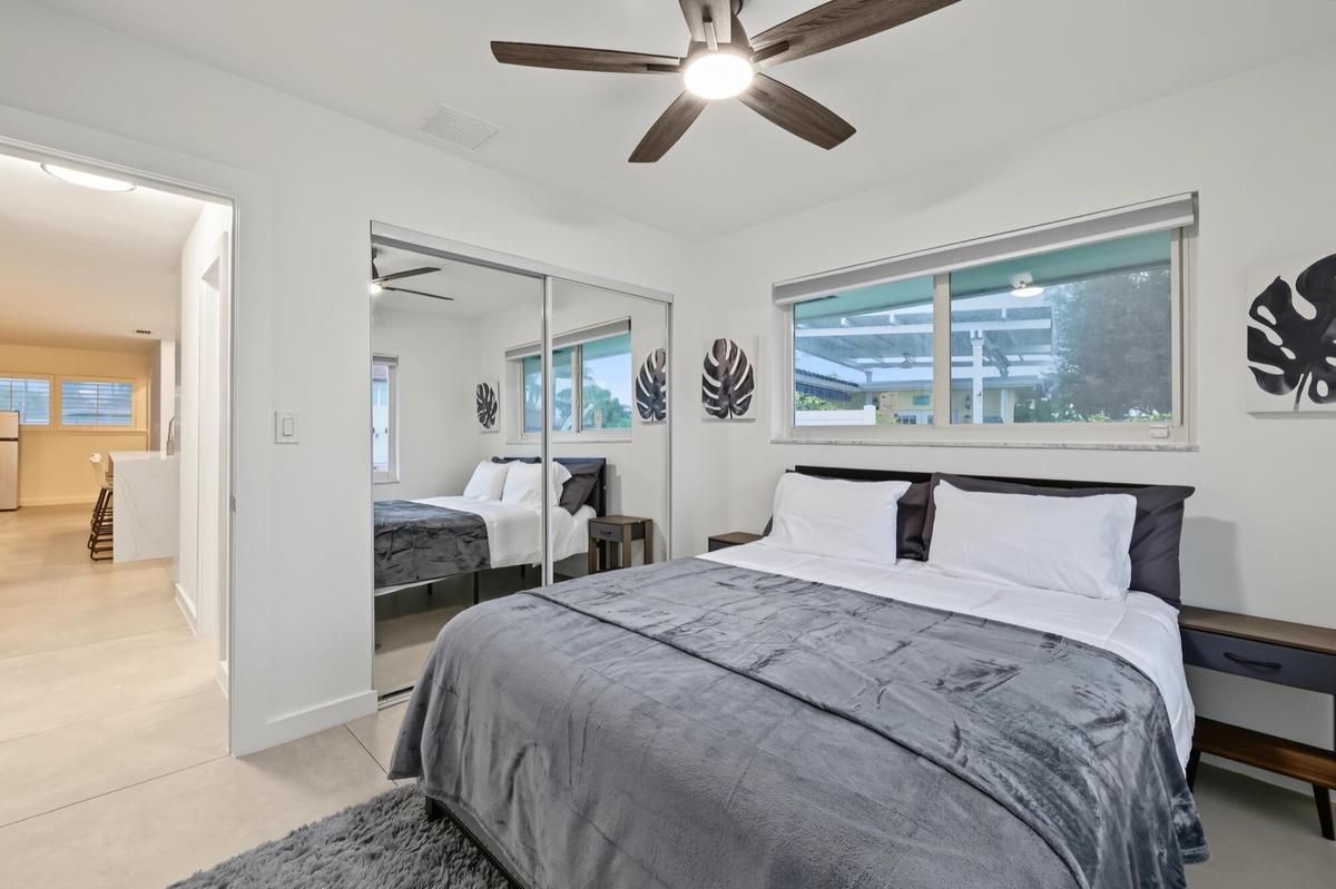 Recessed lighting with a ceiling fan, dual sliding mirror closet doors, and large windows with roller shades