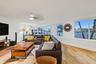 Light wood-finish flooring, recessed ceiling lighting, a ceiling fan, multiple windows with white trim, and white walls