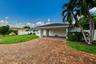 Paved driveway with multi-tone brick pavers, carport, and lush tropical landscaping