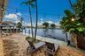Waterfront property featuring a brick paver patio, mature palm trees, and a private dock