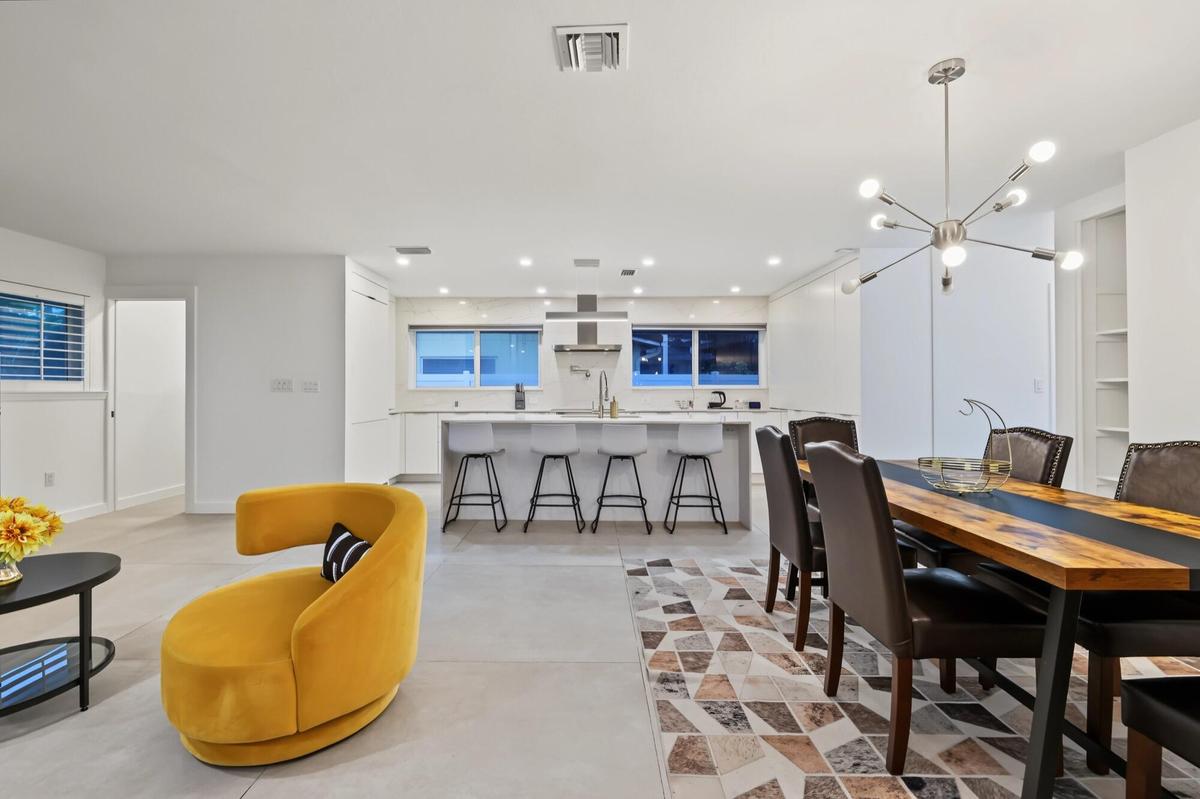 Open-concept living space featuring a modern kitchen with an island, a dining area with a contemporary chandelier, and light-toned flooring throughout