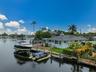 Waterfront property featuring a private boat lift, multiple docking stations, a waterside gazebo, and mature tropical landscaping