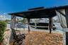 Brick paver patio featuring a black metal gazebo with retractable privacy curtains and a waterfront dock with boat access