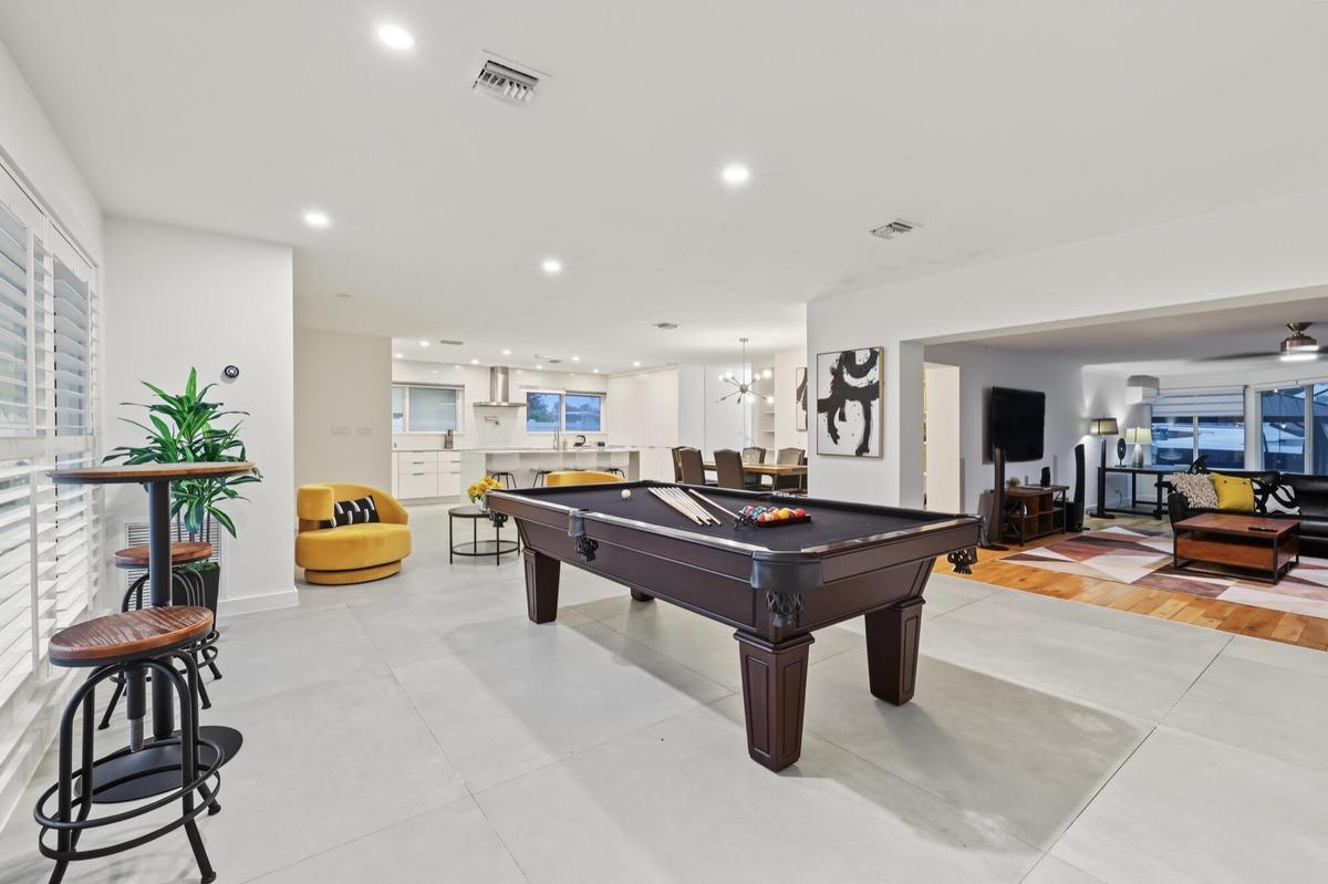 Spacious interior featuring a built-in pool table, recessed lighting, plantation shutters, and light-toned tile flooring