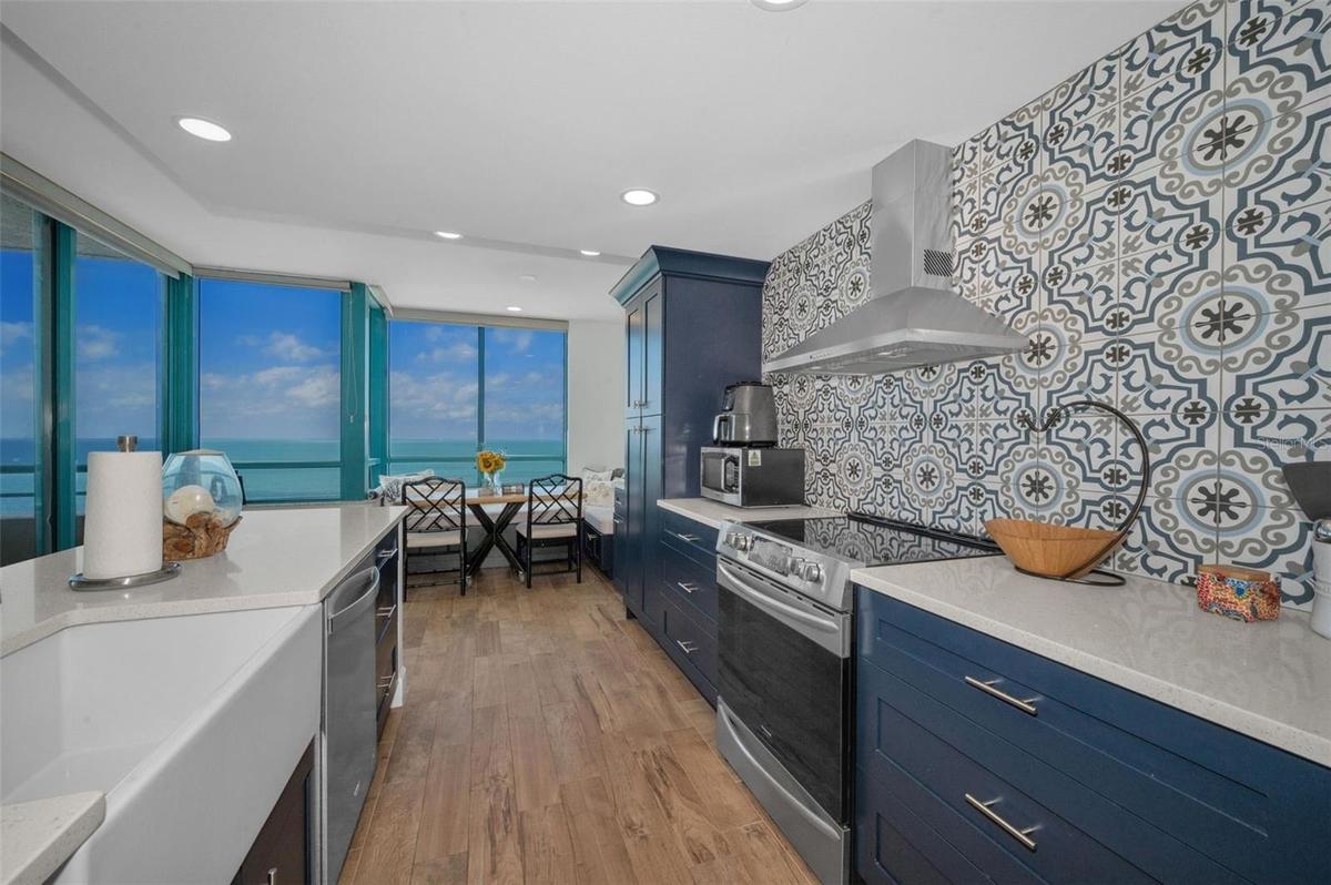Cucina Features Versay Grand Blue Encaustic Style Porcelain Tile Backsplash, Stainless appliances, Quartz Counter Surfaces, Custom Shaker Style Cabine