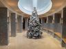 Open circular atrium featuring a skylight, light-toned polished flooring, mosaic-tiled columns, integrated wood benches, and wall-mounted sconces