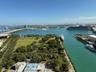 Expansive harbor and city skyline panorama featuring water views, a marine channel, lush parkland, and a distant bridge structure