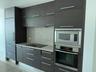 Modern kitchen cabinetry featuring dark wood-finish flat panel doors with brushed nickel hardware