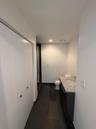 Bathroom featuring dark tile flooring, a single vanity with a light-toned countertop and integrated sink, a toilet, and white walls
