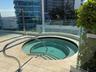 Circular spa with tiled interior, integrated steps, and a stainless steel grab rail