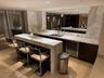 Wet bar featuring stone countertops and backsplash, integrated wine cooler, double basin sink, and recessed lighting