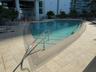 Curved swimming pool with integrated steps, surrounded by light-toned tile decking