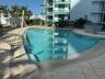 Curved swimming pool featuring a stainless steel handrail, integrated steps, and surrounding tiled deck
