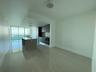 Open-concept living area featuring large format tile flooring, floor-to-ceiling windows, and a modern kitchen with dark cabinetry, integrated applianc