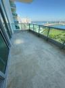 Spacious balcony featuring stone tile flooring, clear glass railings, and expansive water scenery