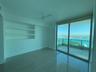 Expansive sliding glass doors opening to a balcony with water and city horizon