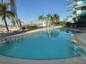 Rooftop swimming pool featuring a curved edge, surrounding tile decking, and metal handrails