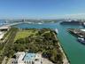 Expansive waterfront panorama showcasing a prominent waterway, an urban skyline, a multi-lane bridge, extensive green spaces, and multiple marine vess